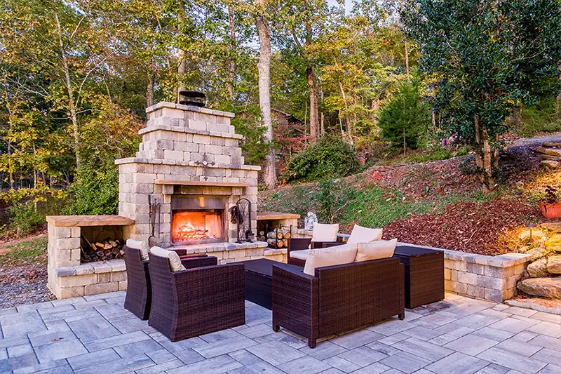 Outdoor Fireplace made of elegant stone/brick design, with storage for firewood, comfy chairs around, on flagstone patios with natural stone steps - O'Fallon, IL